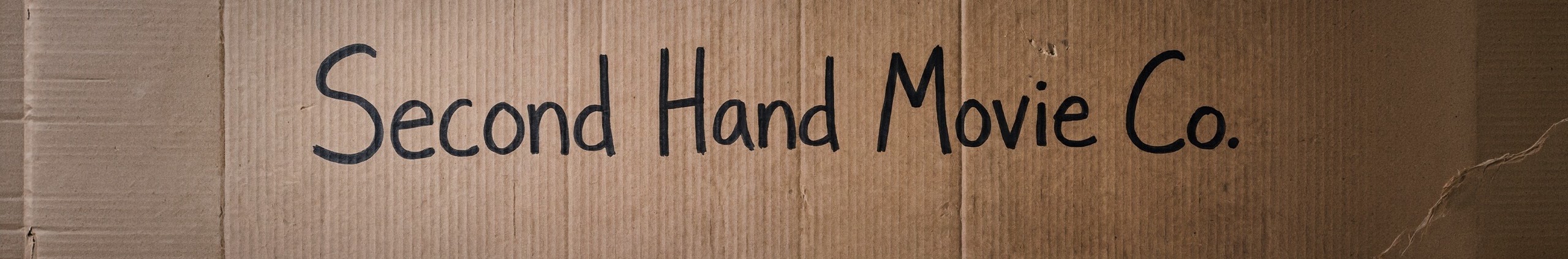 Second Hand Movie Co. — the company name hand-written in marker on a big piece of cardboard